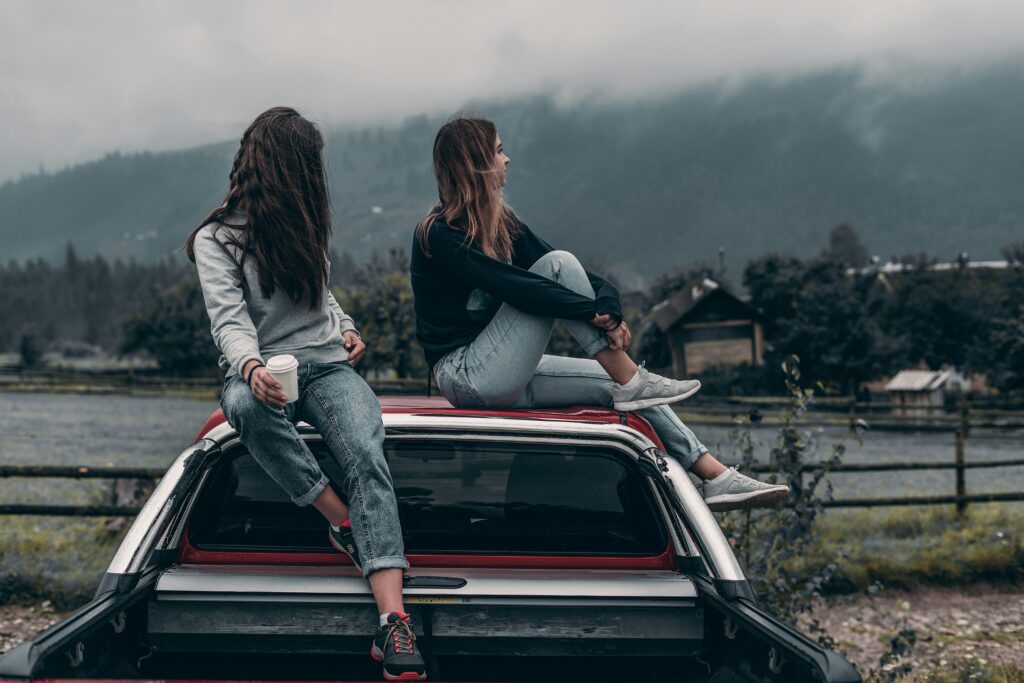 dos chicas sentadas encima de un coche despues de cambiar de nombre el coche a su nombre en Esteve&Fuchs